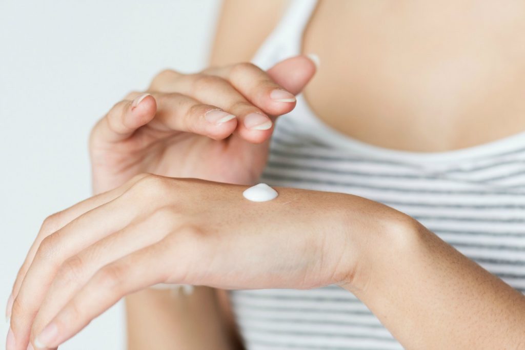Woman moisturising hand - Reasons Eczema Sucks