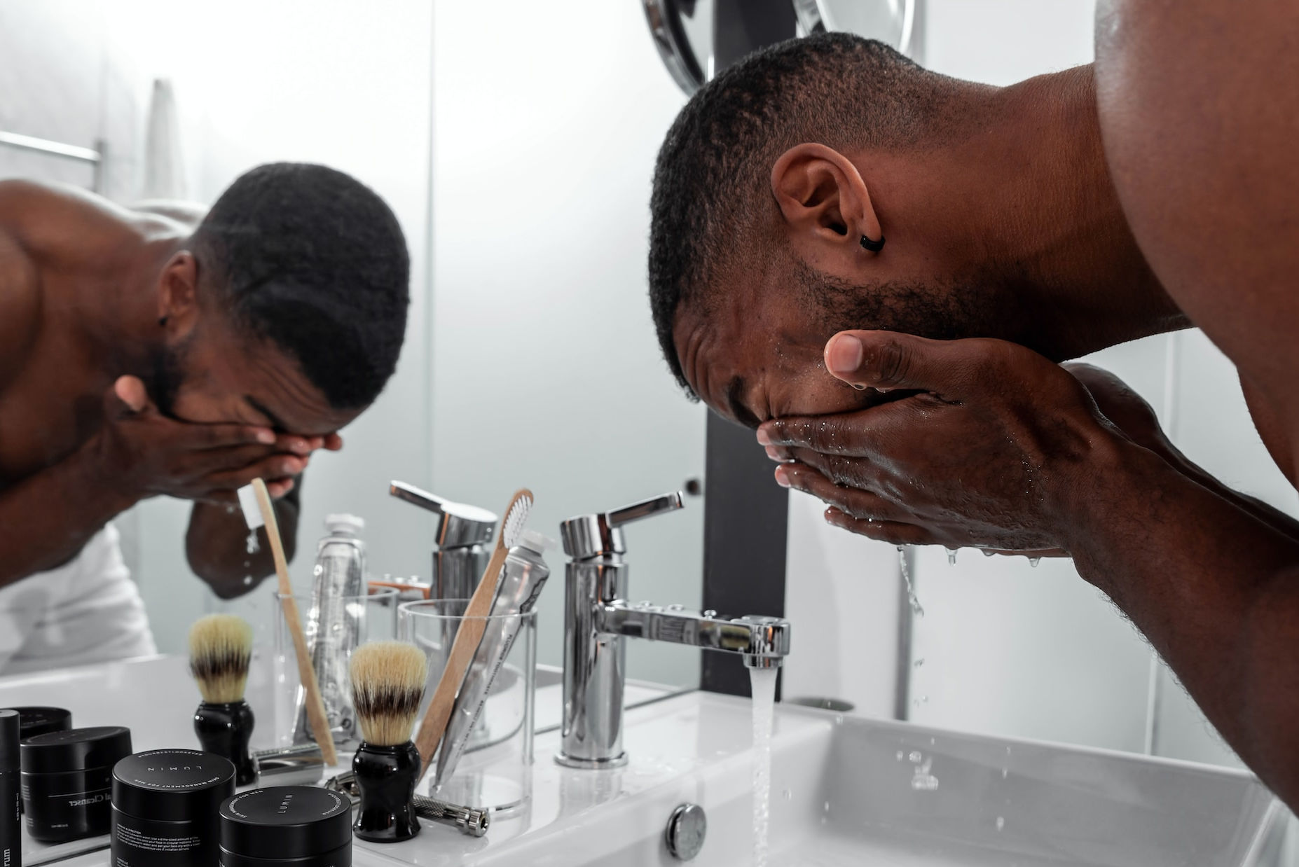 a black man washes his eyes in a bathroom